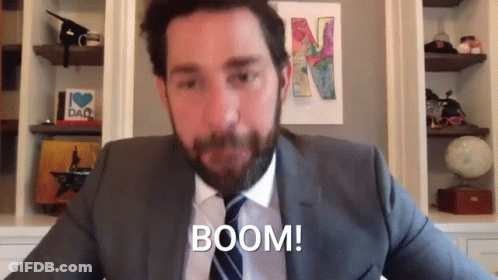 A Man In A Suit And Tie Is Sitting In Front Of A Wall With A Picture Of A Letter N On It . GIF