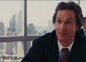 A Man In A Suit And Tie Is Sitting In Front Of A Window Looking Out . GIF