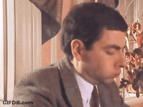 A Man In A Suit And Tie Is Sitting In Front Of A Window With His Eyes Closed . GIF