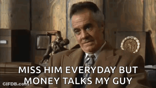 A Man In A Suit And Tie Is Sitting In Front Of A Wooden Wall And Talking About Money . GIF