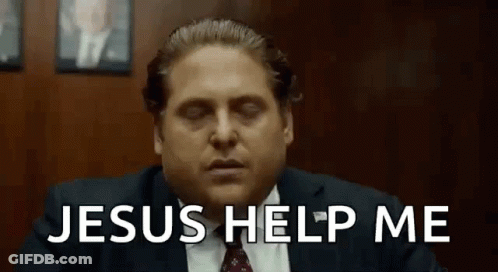 A Man In A Suit And Tie Is Sitting In Front Of A Wooden Wall . GIF