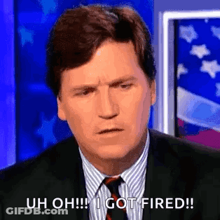 A Man In A Suit And Tie Is Sitting In Front Of An American Flag And Making A Funny Face . GIF
