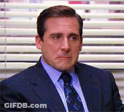 A Man In A Suit And Tie Is Sitting In Front Of Blinds GIF