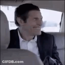 A Man In A Suit And Tie Is Sitting In The Back Seat Of A Car . GIF