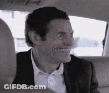 A Man In A Suit And Tie Is Sitting In The Back Seat Of A Car Smiling . GIF