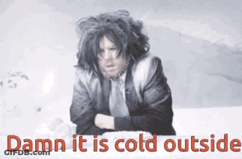 A Man In A Suit And Tie Is Sitting In The Snow With The Words Damn It Is Cold Outside GIF