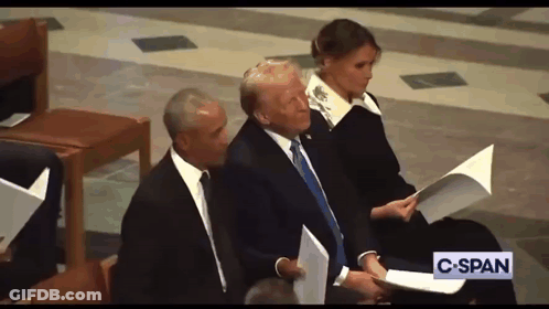 A Man In A Suit And Tie Is Sitting Next To A Woman Holding A Piece Of Paper And A Sign That Says C-Span GIF