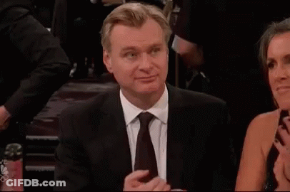 A Man In A Suit And Tie Is Sitting Next To A Woman In A Dress And Clapping . GIF