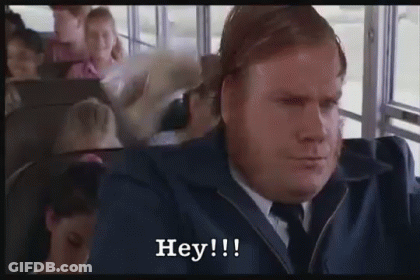 A Man In A Suit And Tie Is Sitting On A Bus And Saying Hey ! GIF