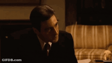 A Man In A Suit And Tie Is Sitting On A Couch And Saying But Your Enemies Closer . GIF