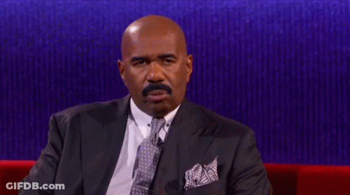A Man In A Suit And Tie Is Sitting On A Couch GIF