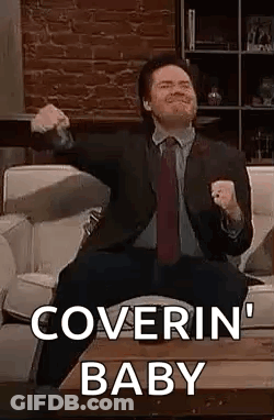 A Man In A Suit And Tie Is Sitting On A Couch With His Arms In The Air . GIF