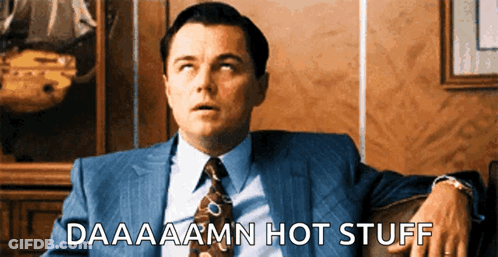 A Man In A Suit And Tie Is Sitting On A Couch With The Words Daaaaamn Hot Stuff Below Him GIF