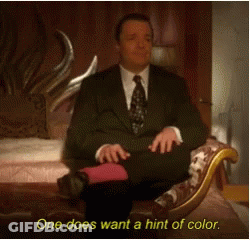 A Man In A Suit And Tie Is Sitting On A Couch With The Words One Does Want A Hint Of Color Below Him GIF