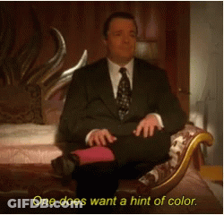 A Man In A Suit And Tie Is Sitting On A Couch With The Words One Does Want A Hint Of Color Below Him GIF