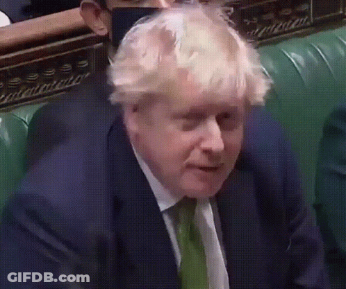 A Man In A Suit And Tie Is Sitting On A Green Chair GIF
