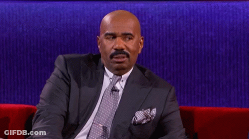 A Man In A Suit And Tie Is Sitting On A Red Couch With His Eyes Closed GIF
