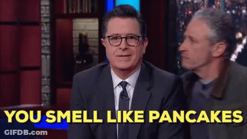 A Man In A Suit And Tie Is Sitting On A Stage And Says You Smell Like Pancakes . GIF