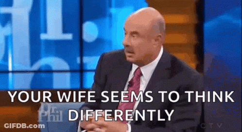 A Man In A Suit And Tie Is Sitting On A Stage And Talking To Someone . GIF