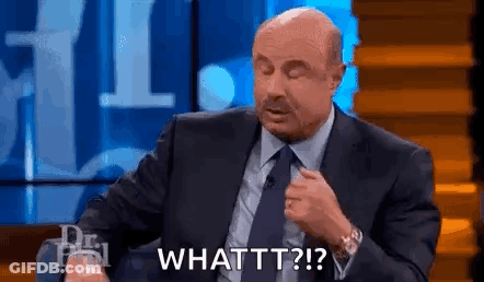 A Man In A Suit And Tie Is Sitting On A Stage With His Eyes Closed And Saying `` Whattt '' . GIF