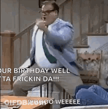 A Man In A Suit And Tie Is Sitting On A Staircase With His Fist In The Air . GIF