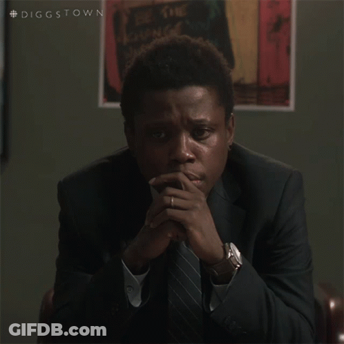 A Man In A Suit And Tie Is Sitting With His Hands Folded In Front Of A Poster That Says Diggstown GIF