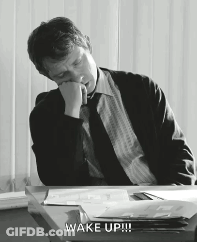 A Man In A Suit And Tie Is Sleeping At A Desk And The Words Wake Up Are Above Him GIF