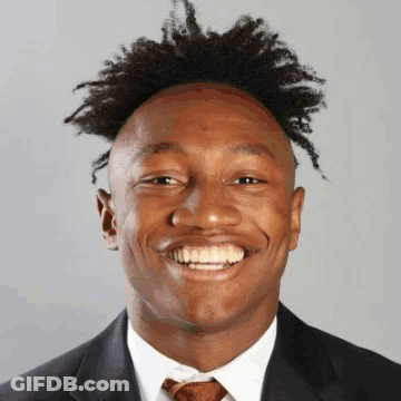 A Man In A Suit And Tie Is Smiling GIF