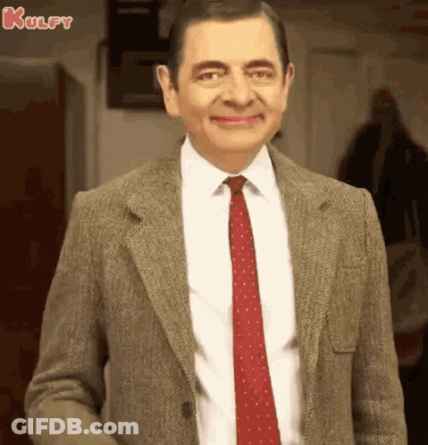 A Man In A Suit And Tie Is Smiling . GIF