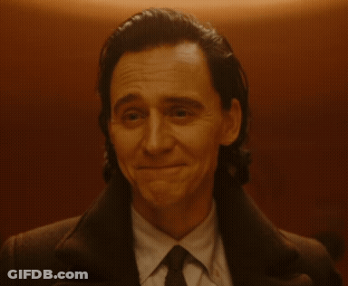 A Man In A Suit And Tie Is Smiling And Looking At The Camera GIF
