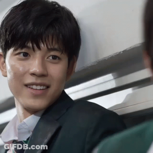 A Man In A Suit And Tie Is Smiling And Looking At The Camera GIF