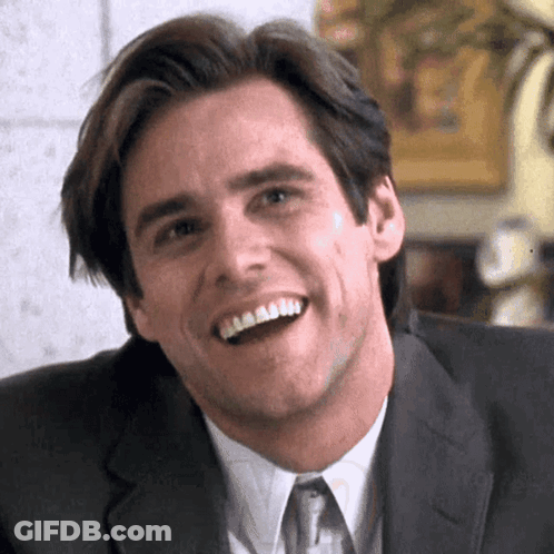 A Man In A Suit And Tie Is Smiling And Looking At The Camera . GIF
