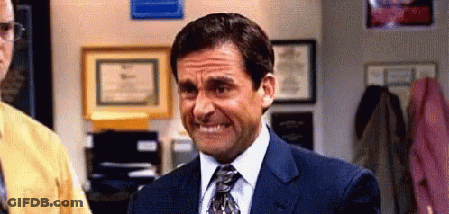 A Man In A Suit And Tie Is Smiling And Making A Funny Face . GIF