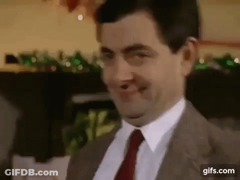 A Man In A Suit And Tie Is Smiling And Making A Funny Face . GIF