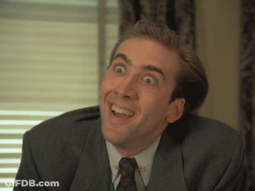 A Man In A Suit And Tie Is Smiling And Making A Funny Face GIF