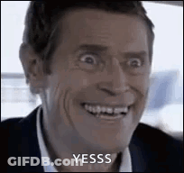 A Man In A Suit And Tie Is Smiling And Making A Funny Face While Sitting In A Car . GIF