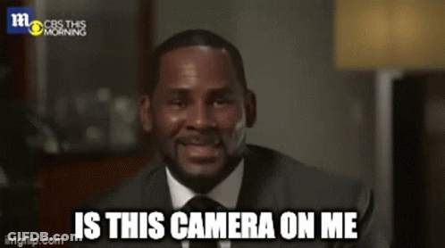 A Man In A Suit And Tie Is Smiling And Saying " Is This Camera On Me " GIF