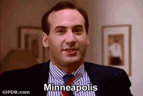 A Man In A Suit And Tie Is Smiling And Saying Minneapolis GIF