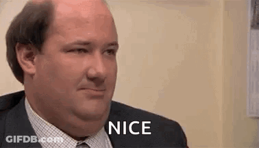 A Man In A Suit And Tie Is Smiling And Saying Nice . GIF