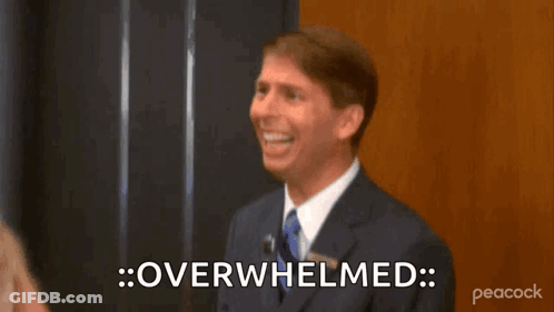 A Man In A Suit And Tie Is Smiling And Saying Overhelmed . GIF
