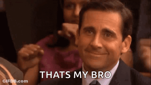 A Man In A Suit And Tie Is Smiling And Saying `` That 'S My Bro '' While Sitting In A Crowd . GIF