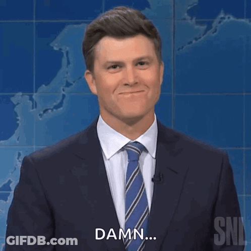 A Man In A Suit And Tie Is Smiling And Says Damn GIF