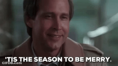 A Man In A Suit And Tie Is Smiling And Says `` Tis The Season To Be Merry . '' GIF