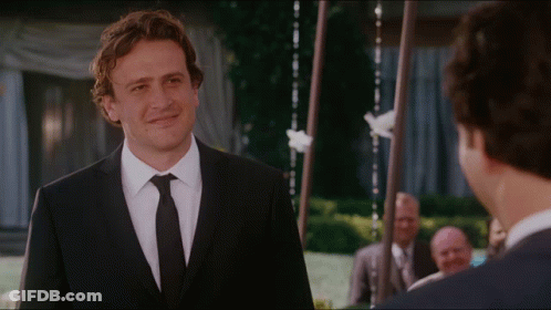 A Man In A Suit And Tie Is Smiling At Another Man GIF