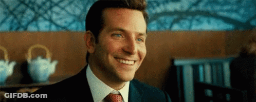 A Man In A Suit And Tie Is Smiling . GIF