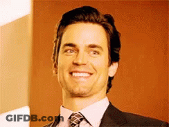 A Man In A Suit And Tie Is Smiling For The Camera GIF