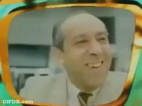 A Man In A Suit And Tie Is Smiling In A Television Screen . GIF