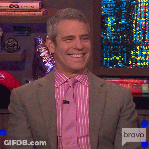 Smiling Man In Suit In Front Of Bravo Sign GIF