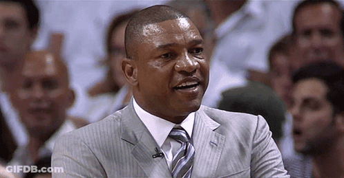 A Man In A Suit And Tie Is Smiling In Front Of A Crowd Of People GIF