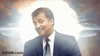 A Man In A Suit And Tie Is Smiling In Front Of A Glowing Light . GIF